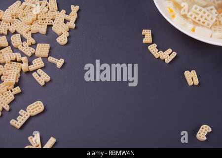 Raw macaroni and white plate with soup on the black background Stock Photo