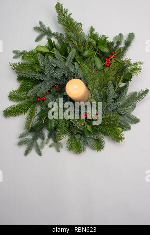 A circle of branches of different fir varieties. Green and blue Nordmann fir branches, coniferous branches and holly (Ilex) lie on white paper backgro Stock Photo