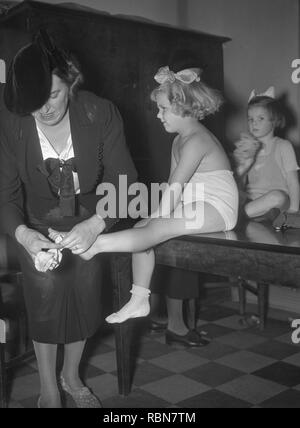 Children in the 1930s. A little girl is getting som help to put on her socks by her mother. Photo Kristoffersson Ref 13-8. Sweden 1939 Stock Photo