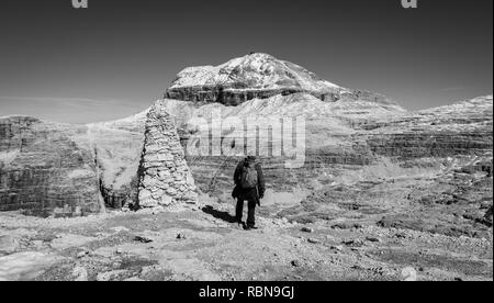 Tourist on the rock of the Sass Pordoi. View towards Piz Boe Mountain, Sella Group, Dolomites, Trentino province, Italy. Image in Black and white Stock Photo