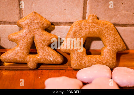 Christmas gingerbreads shaped like a Christmas tree and a house with little pink cookies on the kitchen counter Stock Photo