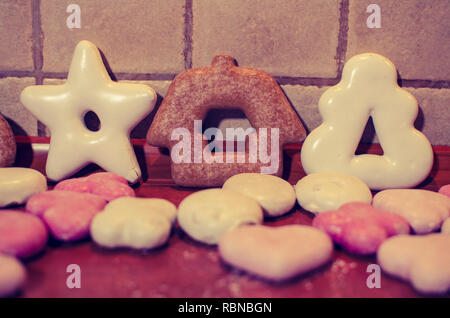 Christmas gingerbreads shaped like a Christmas tree and a house with little pink cookies on the kitchen counter Stock Photo