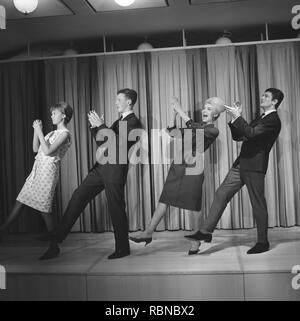 Dancing in the 1960s. The dance Hully Gully is being made popular and here are men and women dancing the new craze. Hully Gully was a type of unstructured line dance and consisted of a series of steps and was relatively simple and easy to execute. Hully Gully can be seen performed by actor John Belushi in the film Blues Brothers. Notice the typical BeeHive hairdo on the blonde girl. Stock Photo