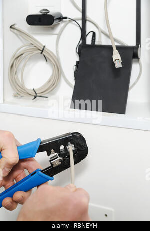Connecting wi-fi router to the Internet. Hands man fixing cable connector using crimp tool. Stock Photo