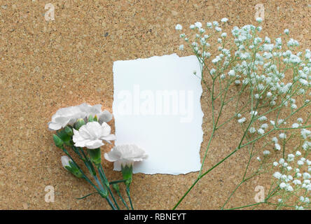 White paper card with flower on wooden corkboard background.Flat lay.feminine concepts design.minimalist style Stock Photo