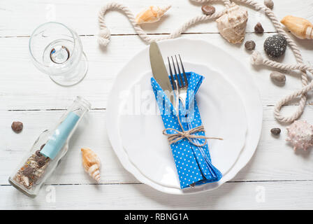 Marine table setting with white dishes and sea decorations at white wooden table. Top view. Stock Photo