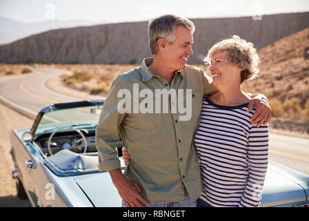 Happy senior couple on road trip standing next to their car Stock Photo