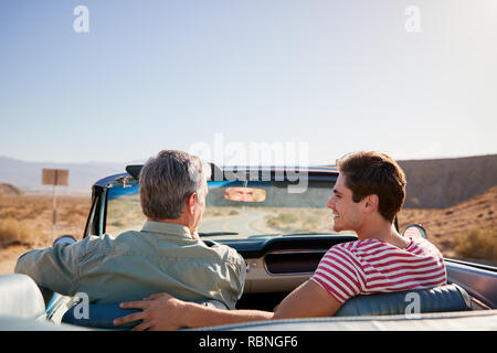 Father and adult son on road trip in open top car, back view Stock Photo