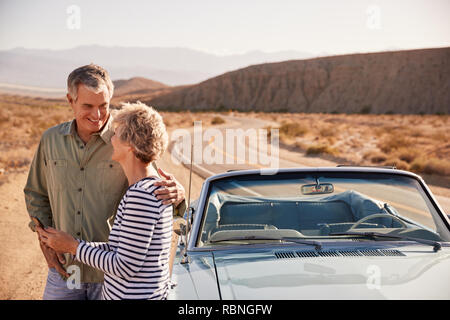 Senior couple checking map on smartphone at desert roadside Stock Photo