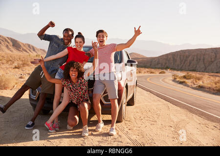 Young adult friends on road trip have fun posing by the car Stock Photo