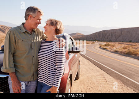 Senior couple stand looking at each other on desert roadside Stock Photo