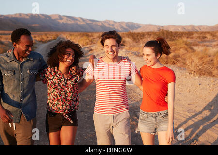 Four young adult friends laughing on a desert road, close up Stock Photo