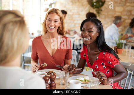 Young female friends smiling at brunch in a cafe, close up Stock Photo