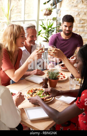 Adult friends eating in a cafe making a toast, vertical Stock Photo