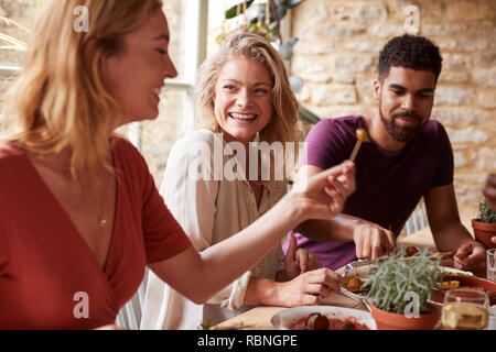 Three young friends having fun eating tapas at a restaurant Stock Photo