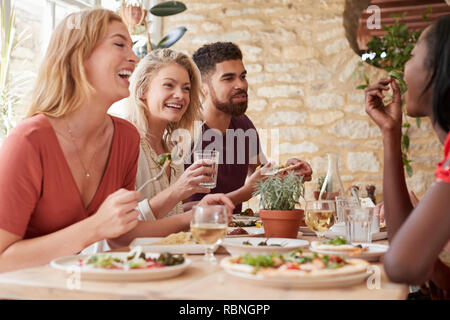 Four young adult friends eating in a restaurant, close up Stock Photo