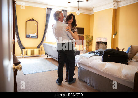 Middle aged couple embrace,  smiling in their hotel room Stock Photo