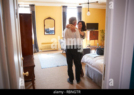 Mature couple embrace, looking at each other, in hotel room Stock Photo