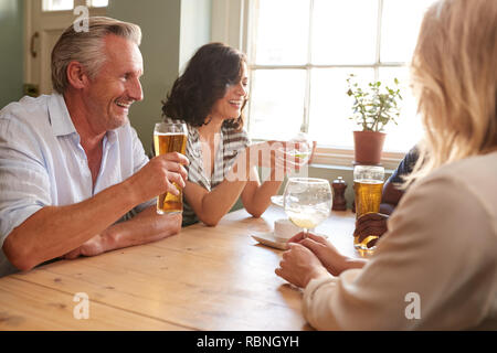 Mature adult friends drinking at a table in a pub Stock Photo