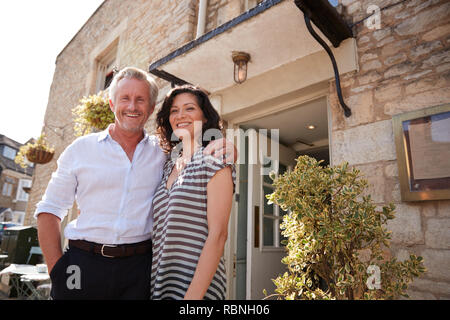 Mature business couple standing outside their restaurant pub Stock Photo