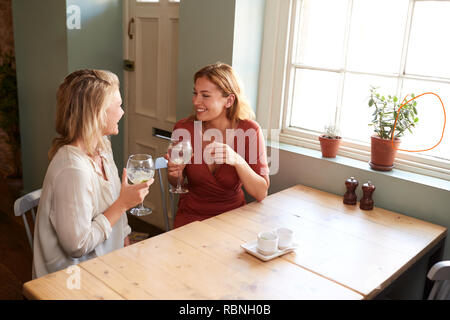 Two young female friends talking over drinks in a pub Stock Photo