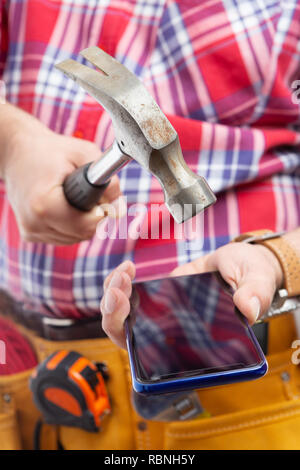 Close-up of constructor trying to break smartphone display with hammer as anger gesture isolated on background Stock Photo