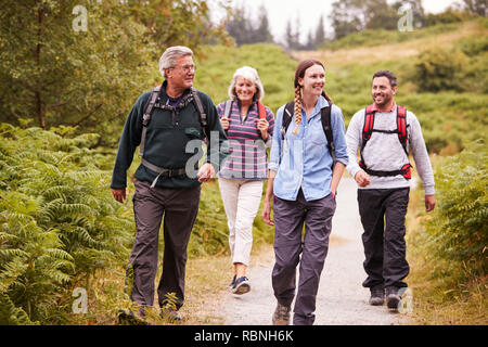 Two mixed age couples walking on a countryside path during family camping adventure, front view Stock Photo