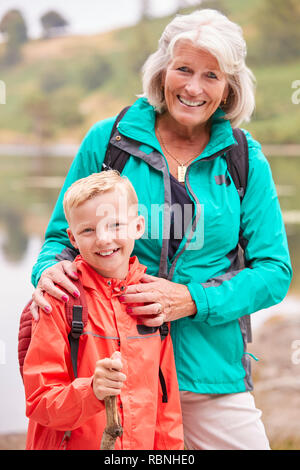 Grandmother and grandson standing together near a lake in the countryside smiling to camera, close up, Lake District, UK Stock Photo