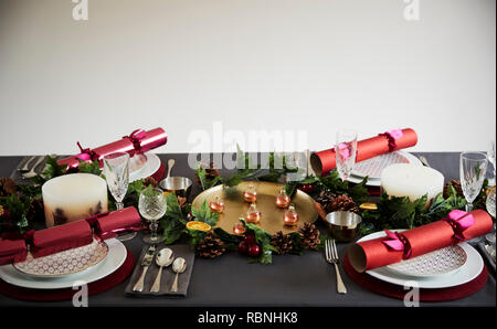 Decorated Christmas table set for four people, with Christmas crackers arranged on plates Stock Photo