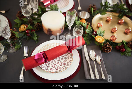 Close up of Christmas table setting with Christmas crackers arranged on plates, elevated view Stock Photo