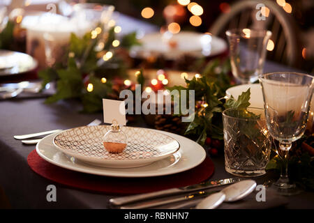 Christmas table setting with bauble name card holder arranged on a plate and green and red table decorations Stock Photo