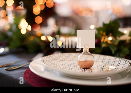 Close up of Christmas table setting with bauble name card holder arranged on a plate and green and red table decorations Stock Photo