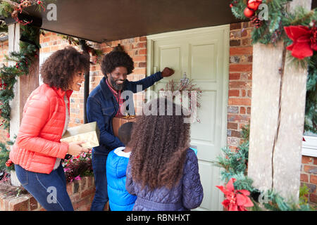 Family Knocking On Front Door As They Arrive For Visit On Christmas Day With Gifts Stock Photo