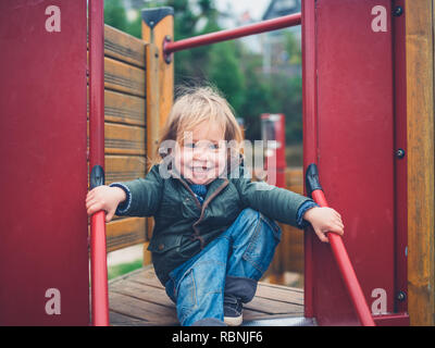 A little toddler is coming down the slide in a park Stock Photo