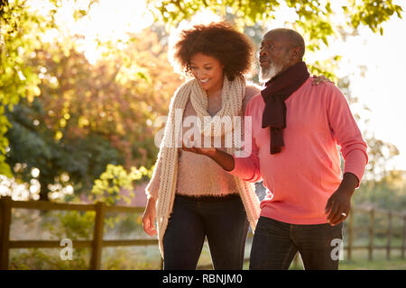 Senior Father With Adult Daughter Enjoying Autumn Walk In Countryside Together Stock Photo