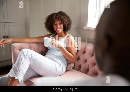 Young adult black couple sit drinking coffee looking at each other in the morning, over shoulder view, close up Stock Photo