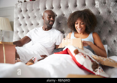 Young adult black couple opening gifts in bed on Christmas morning, low angle Stock Photo