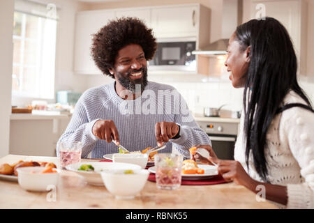Happy black couple enjoying eating their Sunday dinner together at home, close up Stock Photo