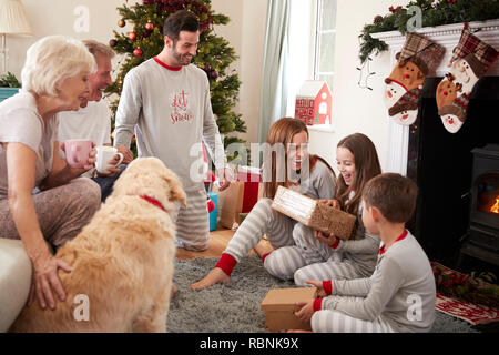 Three Generation Family Wearing Pajamas In Lounge At Home Opening Gifts On Christmas Day Stock Photo