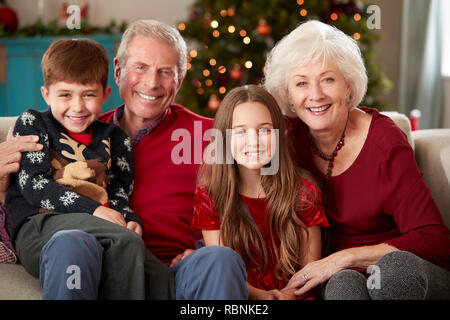 Portrait Of Grandparents With Grandchildren Sitting On Sofa In Lounge At Home On Christmas Day Stock Photo