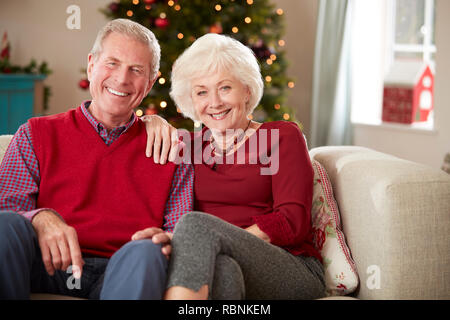 Portrait Of Senior Couple Sitting On Sofa In Lounge At Home On Christmas Day Stock Photo