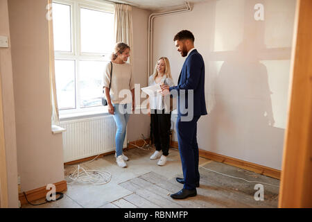 Two Female Friends Buying House For First Time Looking At House Survey With Realtor Stock Photo