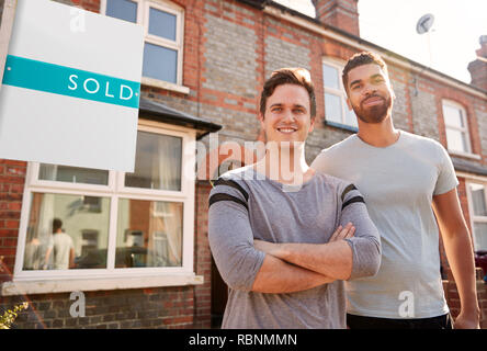 Portrait Of Two Men Standing Outside New Home With Sold Sign Stock Photo