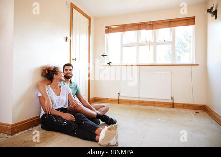 Couple Sitting On Floor In Empty Room Of New Home Planning Design Stock Photo