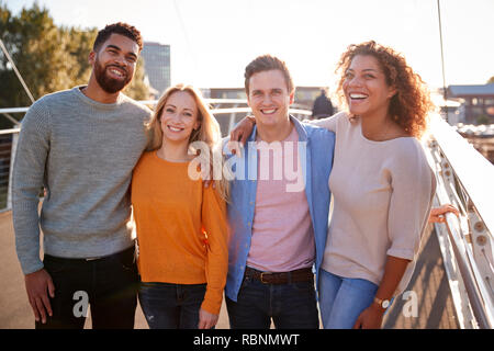 Portrait Of Young Friends Walking Across City Bridge Together Stock Photo