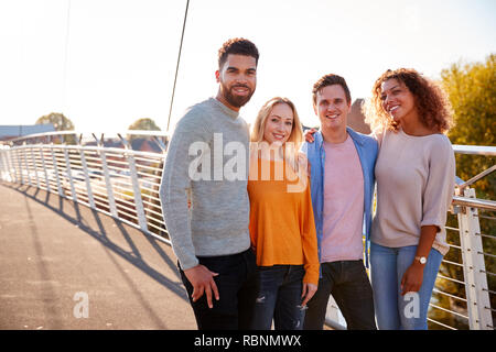 Portrait Of Young Friends Walking Across City Bridge Together Stock Photo