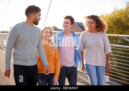 Group Of Young Friends Walking Across City Bridge Together Stock Photo