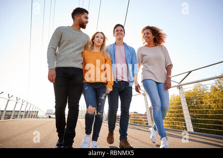 Group Of Young Friends Walking Across City Bridge Together Stock Photo