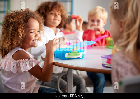 Close up of smiling young children sitting at a table eating their packed lunches together at infant school, selective focus Stock Photo