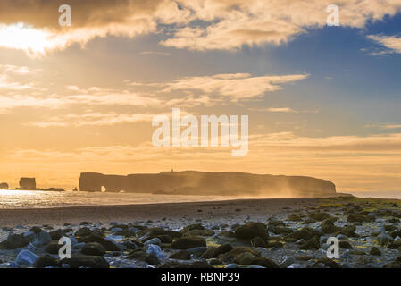 big flat rock in the ocean with surge in foreground in sunset mood Stock Photo